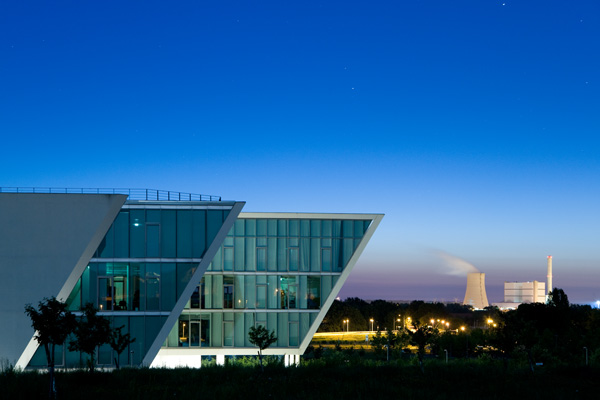 nachtaufnahme vom mlc gebäud mit dunkelblauem himmel und dem heizkraftwerk west im hintergrund